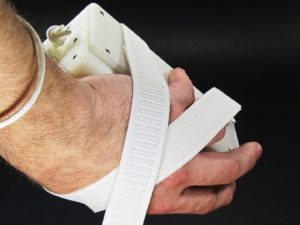 Palm Writer Being Gripped In Bottom Perspective View Showing Wrist Strap Around Users Wrist, Wrist Rest, and Crossed and Attached Suspension Strap